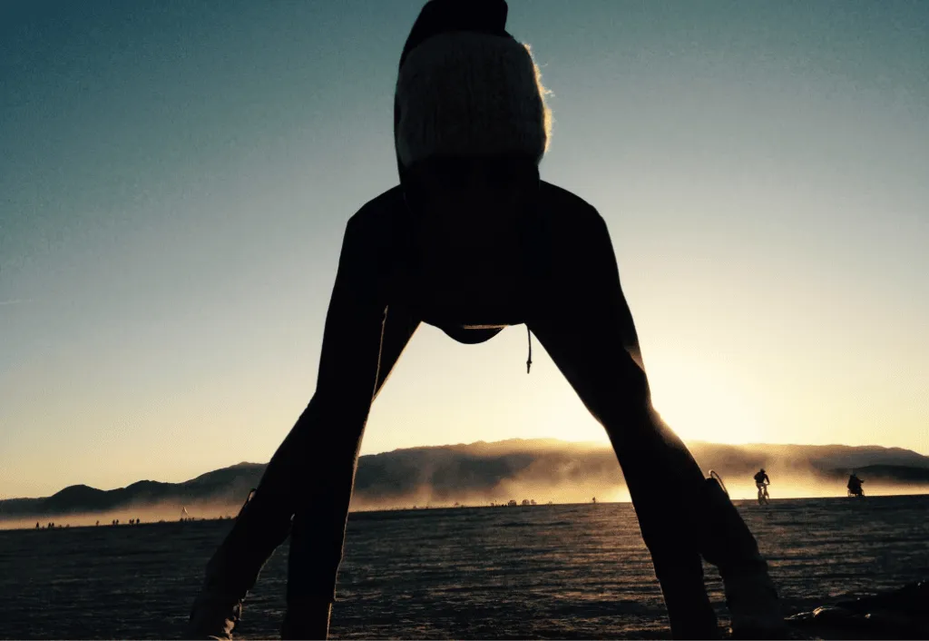 Silhouetted figure in wide-legged grounded stance at dawn — body wisdom and somatic awareness
