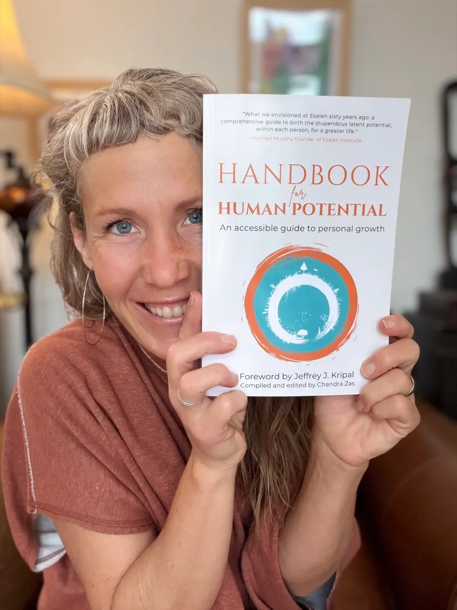 Chandra Zas holding her book Handbook for Human Potential — Esalen foreword by Michael Murphy, edited and compiled by Chandra Zas