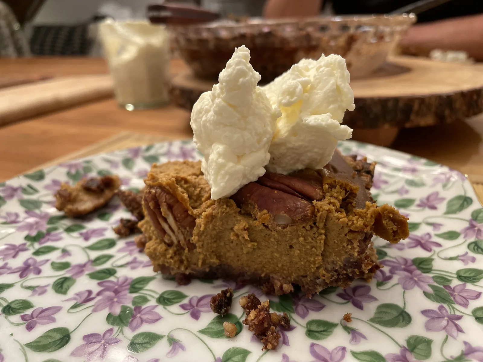 A whole homemade pumpkin pie in a 9-inch glass pan with a deeply golden date-pecan crust and a smooth spiced filling, cooling on a wire rack