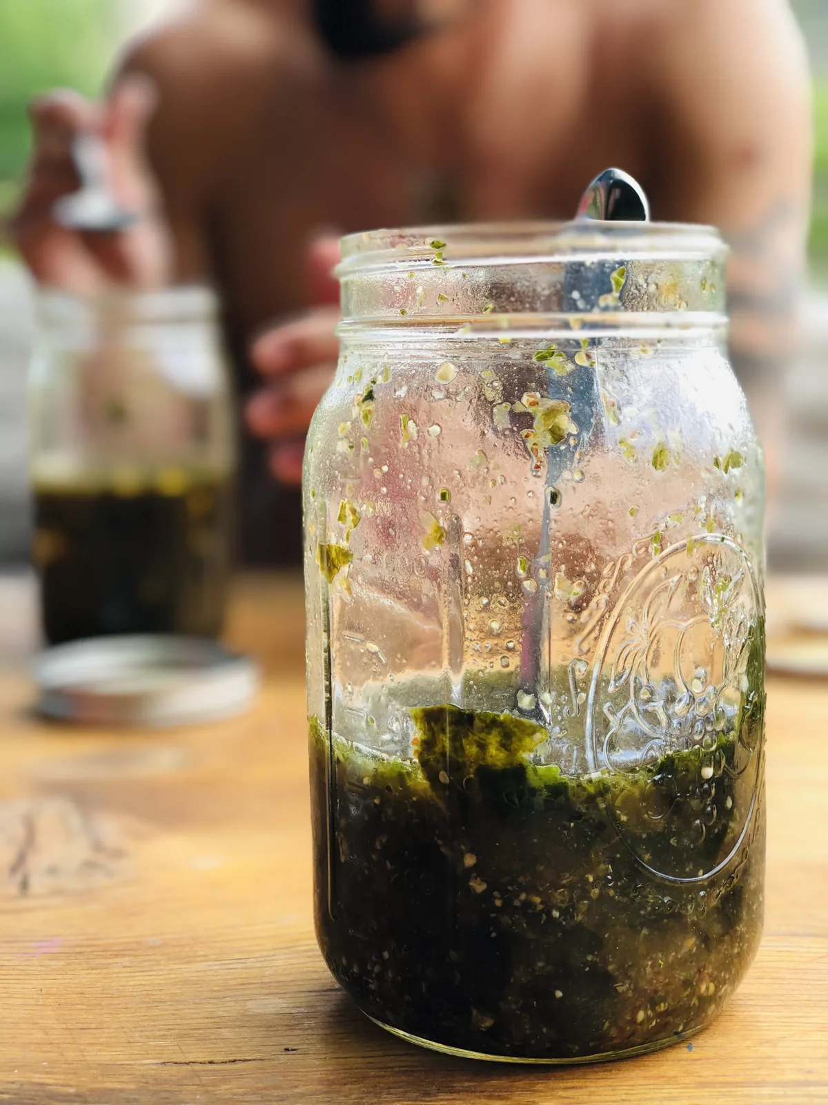 A mason jar of fully assembled bone broth soup on a wooden outdoor table, ready to drink