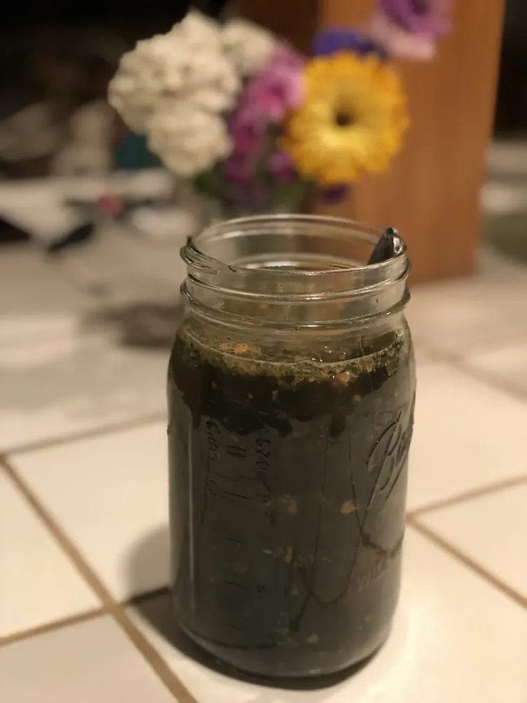 Mason jar of assembled bone broth ingredients ready for hot water, with miso, wakame, kale flakes, and tahini visible