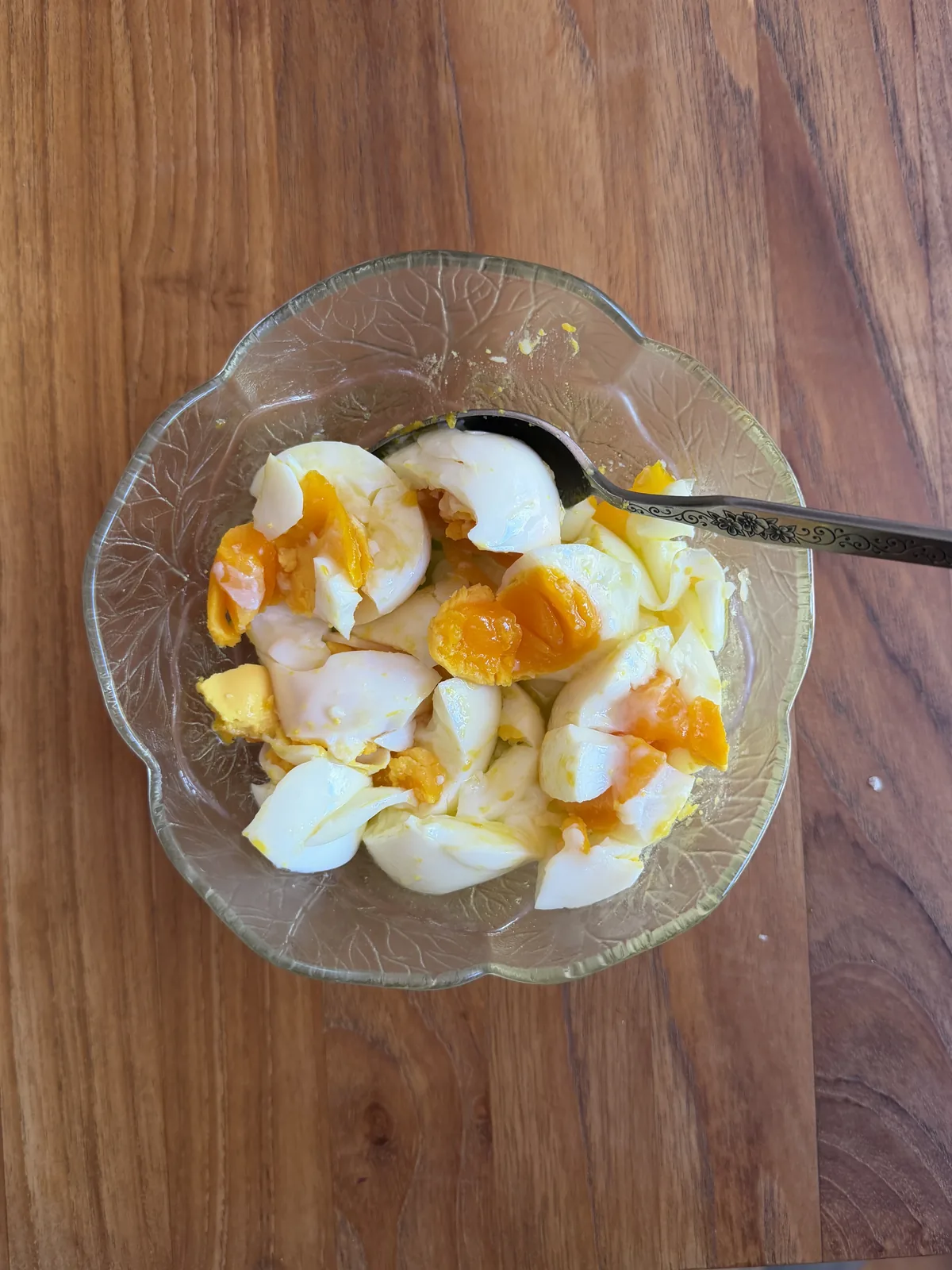 Two halved soft-boiled eggs in a small bowl, soft runny orange yolks, drizzled with good olive oil and finished with flaky sea salt